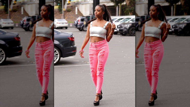 Person walking with distressed pink skinny jeans and a crop top