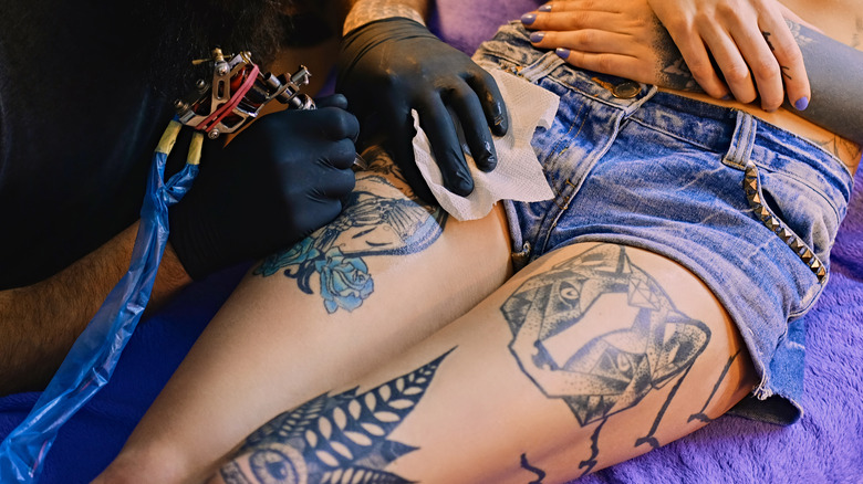 Woman getting leg tattoo