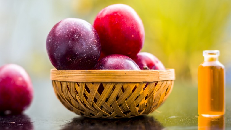 Basket of plums and oil vial