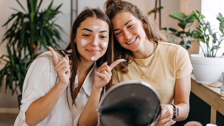 Woman applying skincare with best friend