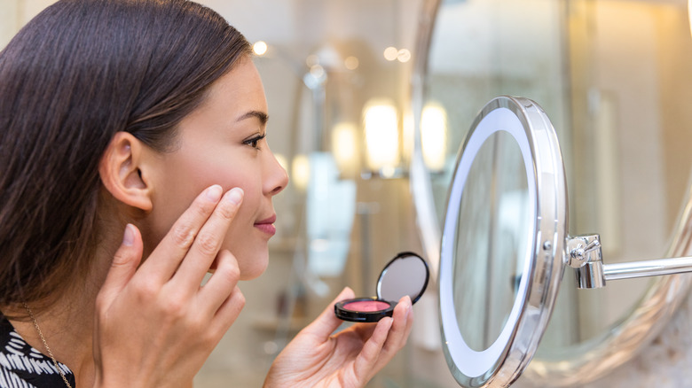 woman touching up cream blush