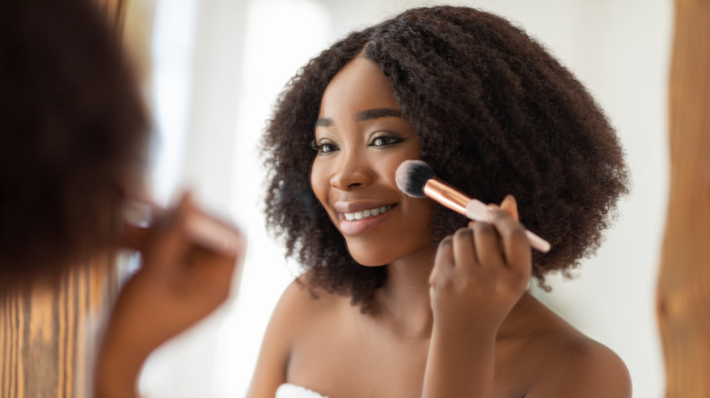 smiling woman applying blush