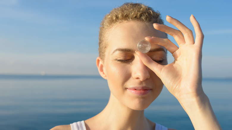 Woman holding crystal to forehead 