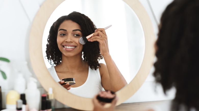 Woman applying makeup to person