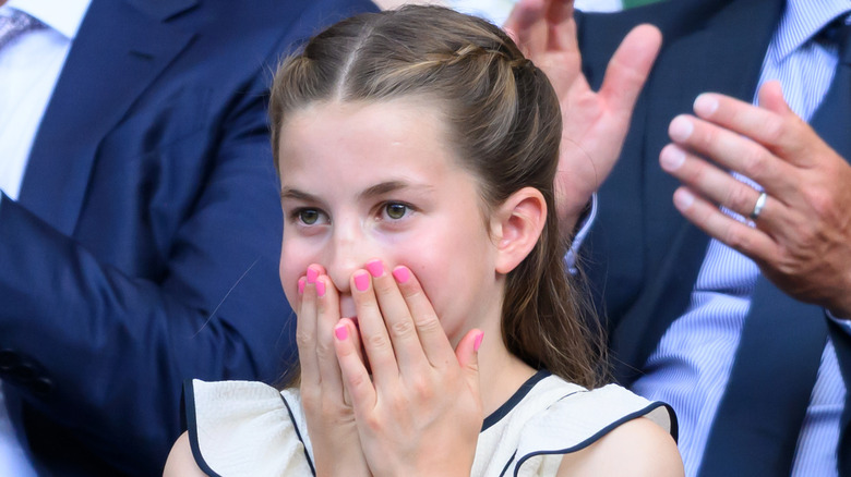 Princess Charlotte pictured at Wimbledon in 2025 with her hands on her mouth wearing pink nail polish..