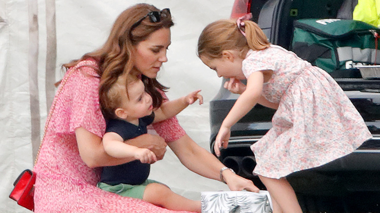 Princess Charlotte grabs a snack from a cooler by her mom, Kate Middleton, and brother, Prince Louis