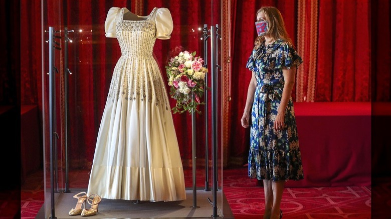 Princess Beatrice, wearing a mask, admires her wedding dress on display