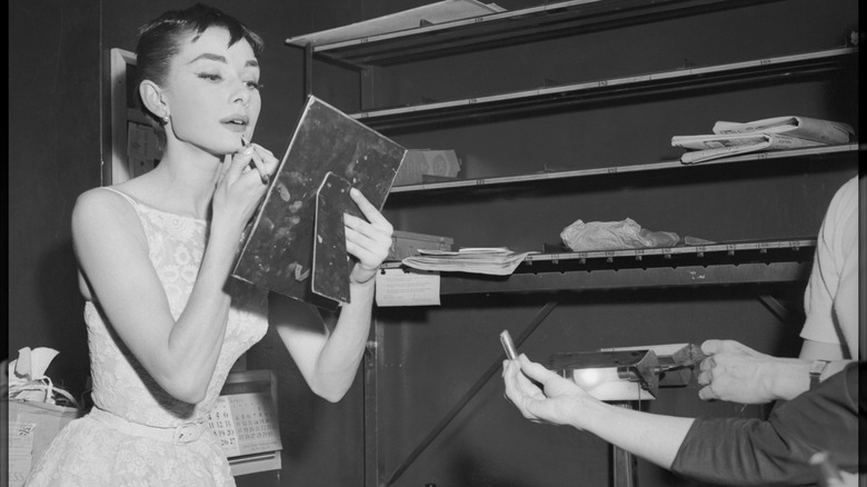 Audrey Hepburn uses a mirror to touch up her makeup in the dressing room of the Center Theater on the night she won the Best Actress Oscar at the 26th annual Academy Awards in March 1954