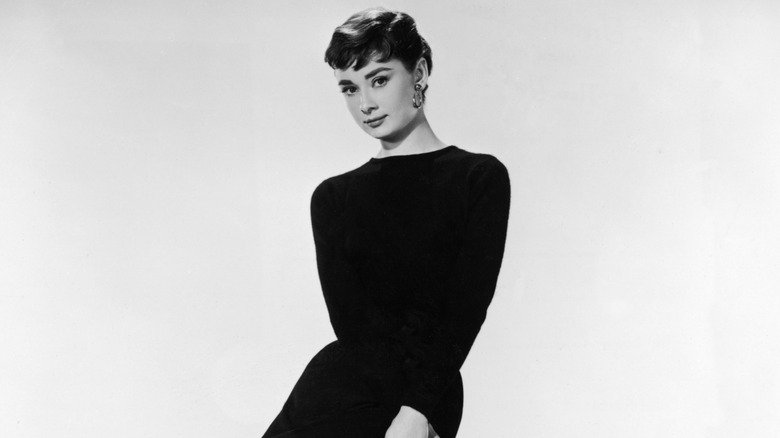 Audrey Hepburn sitting on a stool in 1954 for a promo photo for the film 