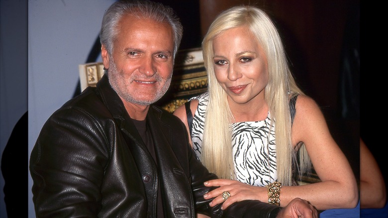 Gianni Versace in a black leather jacket sitting next to sister Donatella wearing a black-and-white top circa 1996.