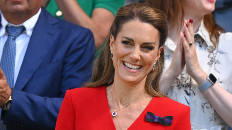 Kate Middleton smiling while wearing a red dress