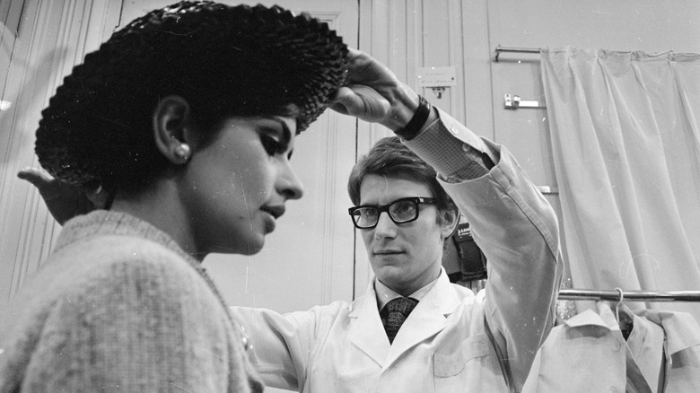 Yves Saint Laurent fixing a model's hat