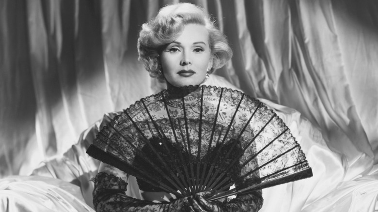 A black-and-white portrait of Zsa Zsa Gabor with a huge fan.