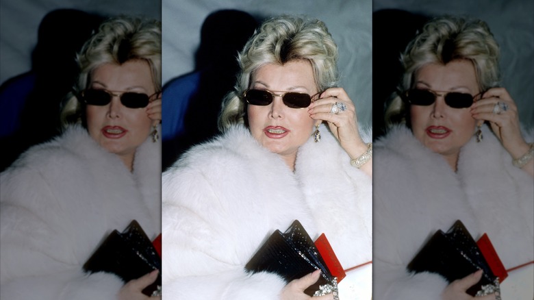 Zsa Zsa Gabor out in NYC in 1984 wearing sunglasses and a white fur coat.