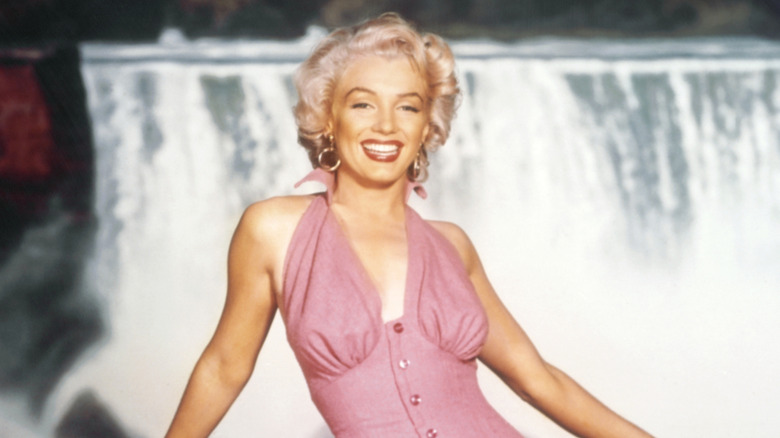 Marilyn Monroe wearing a pink dress posing for a photo on the set of Niagara