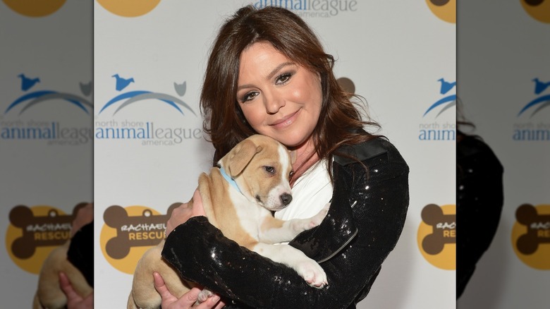 Rachael Ray cuddles with a puppy on a red carpet