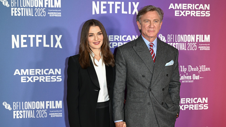 Rachel Weisz wearing a black suit posing with Daniel Craig