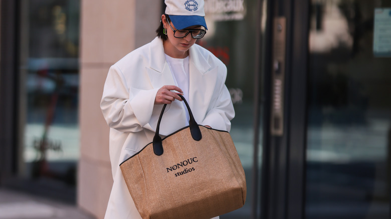 person holding raffia tote bag