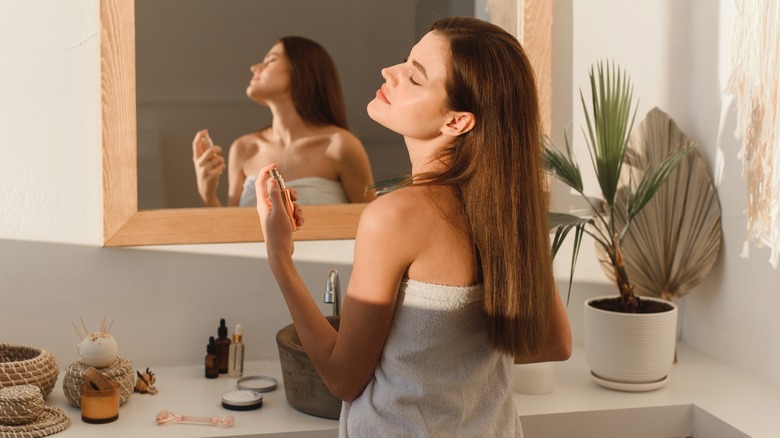 Girl wearing towel spraying perfume