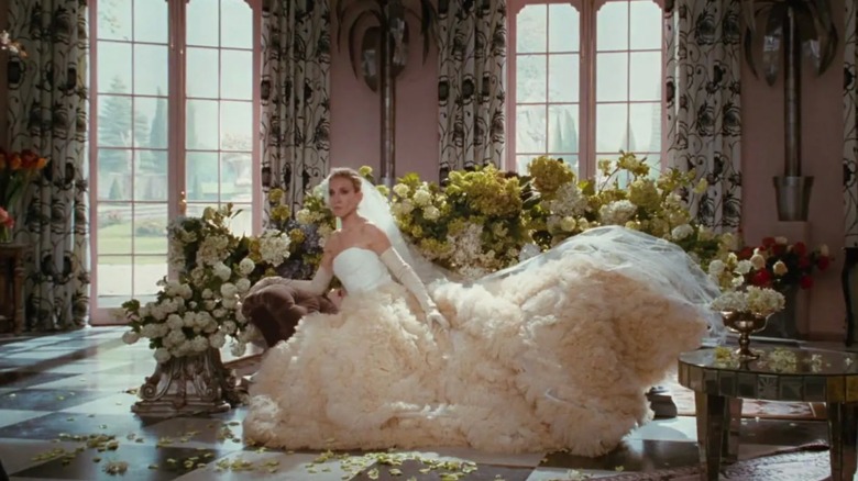 Sarah Jessica Parker as Carrie Bradshaw sitting down wearing a statement ballgown wedding dress and gloves
