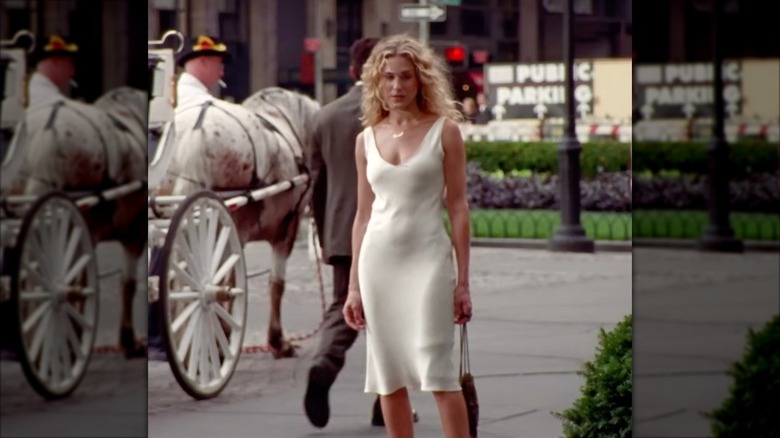 Sarah Jessica Parker as Carrie Bradshaw wearing a off-white satin slip dress.