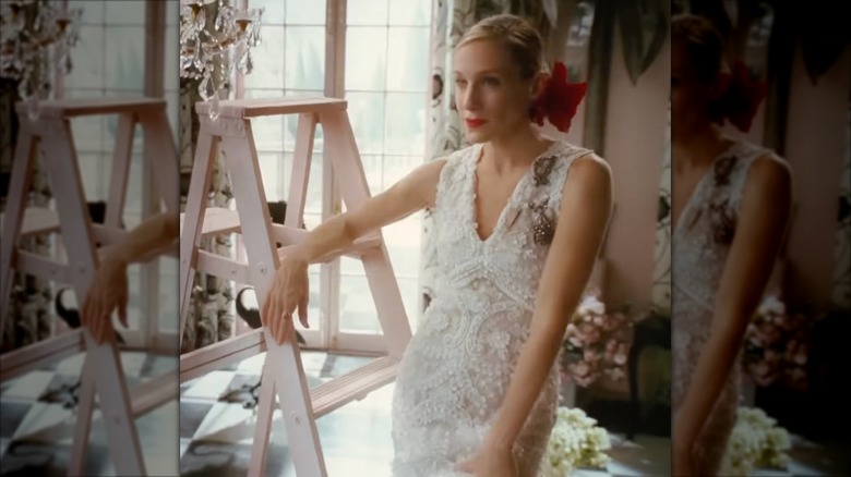 Sarah Jessica Parker as Carrie Bradshaw wearing a lace fishtail wedding dress with a red flower in her hair.