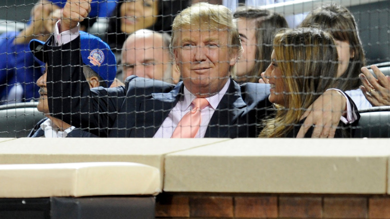 Melania Trump smiling at Donald Trump who is giving a thumbs up to the camera at a baseball game