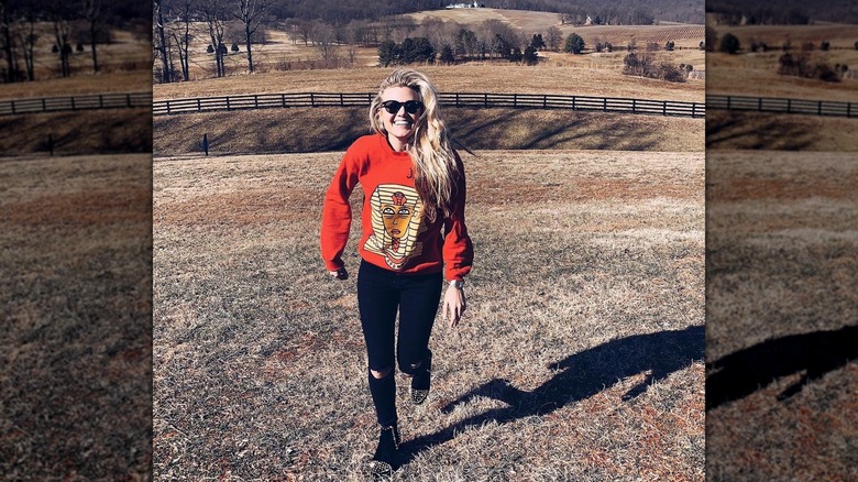 Erika Kirk in an orange pharaoh sweater and black skinny jeans