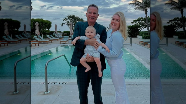 Karoline Leavitt posing in white pants and a blue top by the pool with her husband and son.