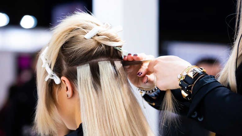hairdresser applying tape-in extensions