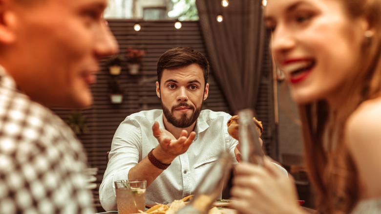 a man looking perplexed at a happily laughing couple