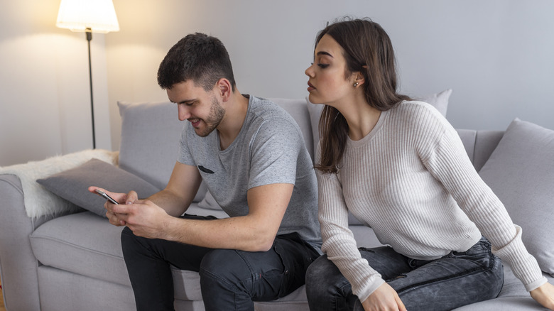 woman looking at boyfriend's phone