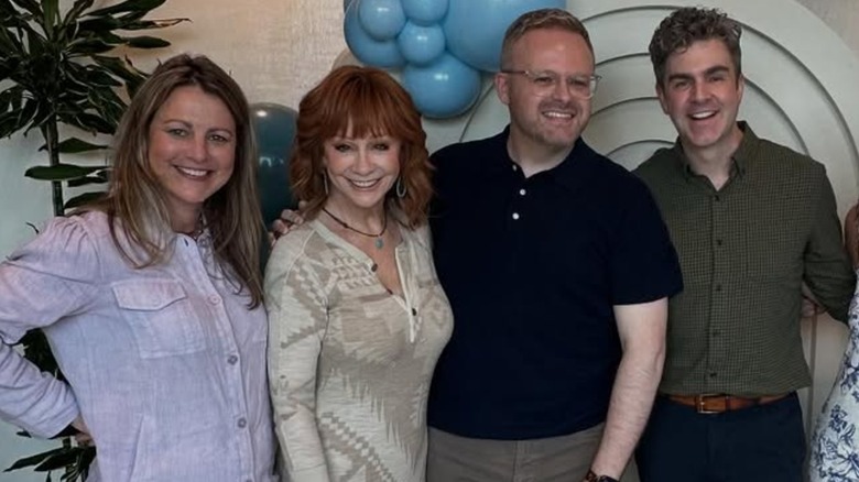 Reba McEntire smiling while posing with friends at an event