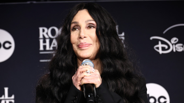 Cher smiling while holding a microphone