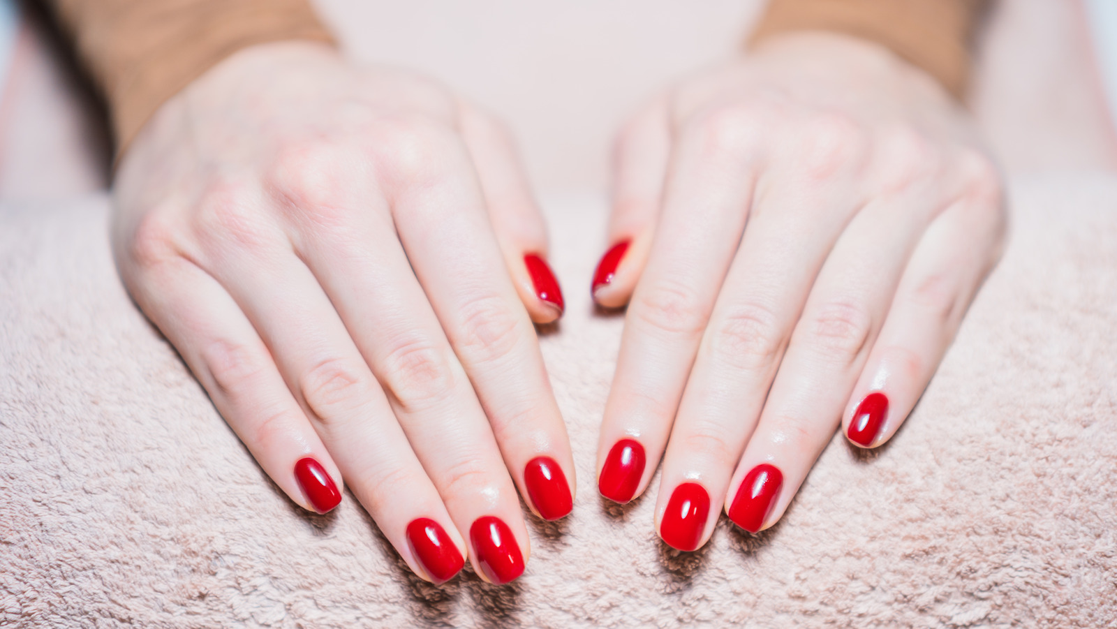 Red nail polish. Hand with red nails on a white background. Close up of  female hands
