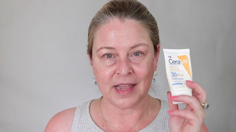 Woman holding up CeraVe hydrating sunscreen