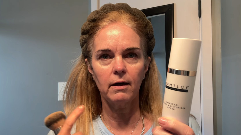Woman holding up DRMTLGY tinted moisturizer