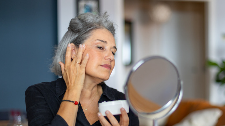 Mature woman applying skincare product