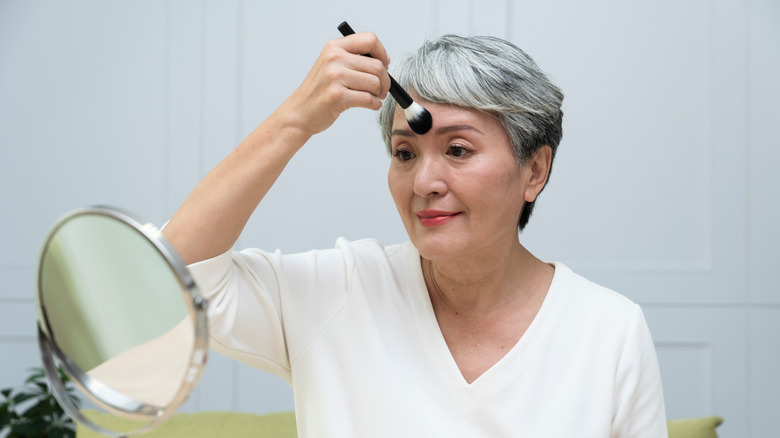 Mature woman applying makeup