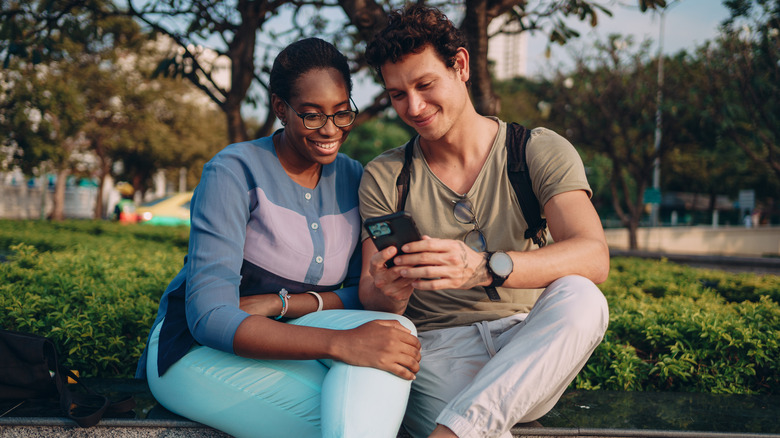 couple on bench looking at phone