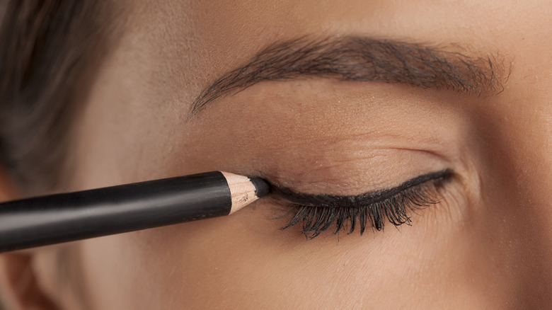 woman applying black eyeliner