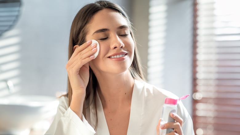 Woman applying skincare products to face