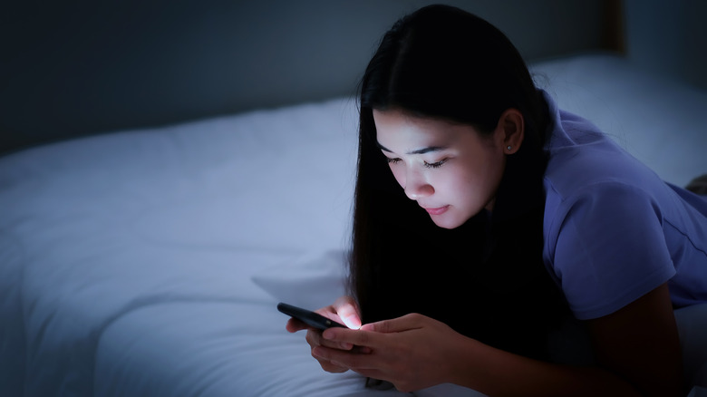 Woman using phone in bedroom