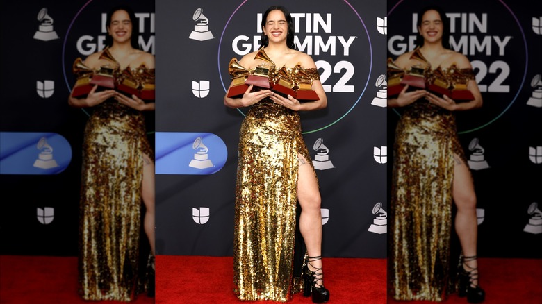 Rosalía wearing gold dress and black platform shoes