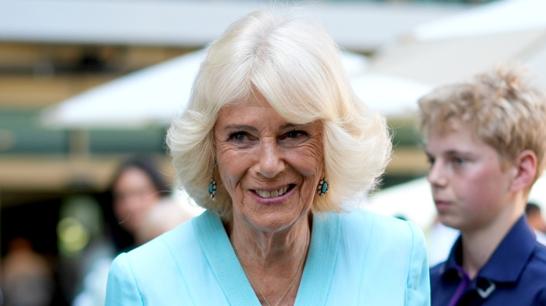 Queen Camilla wears a feathered bob and blue suit jacket