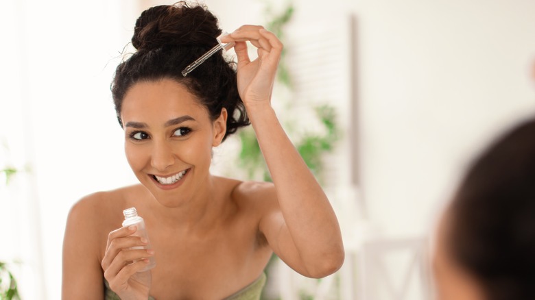 woman applying serum to scalp