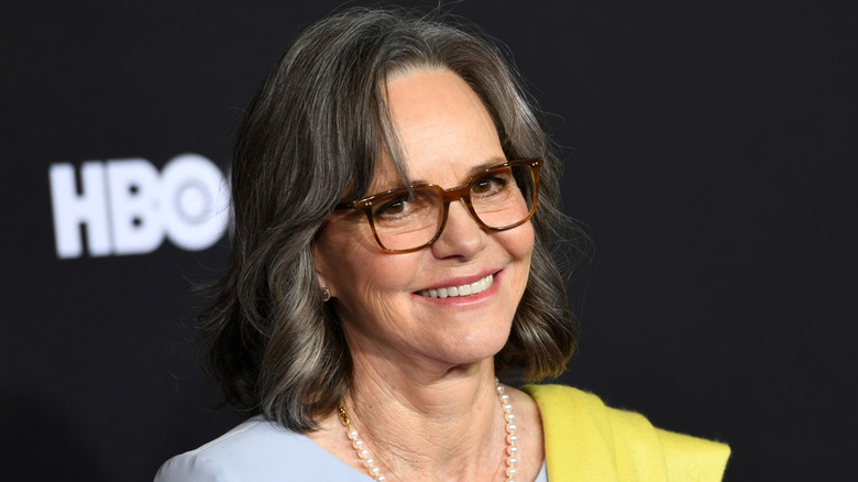 Sally Field wears a pearl necklace and glasses in a pastel blue and yellow outfit on the red carpet