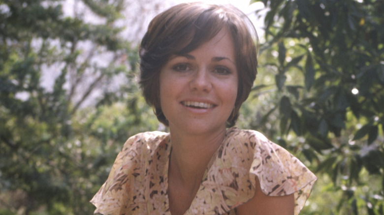 Sally Field smiling with short hair and trees in the background