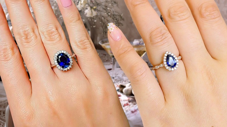 Hands displaying sapphire halo engagement rings