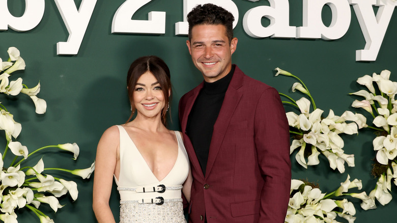 Sarah Hyland in a creme dress standing next to Wells Adams in a burgundy suit at the Baby2Baby gala.